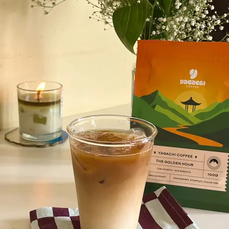 Iced coffee next to a bag of Yagachi Coffee and a candle